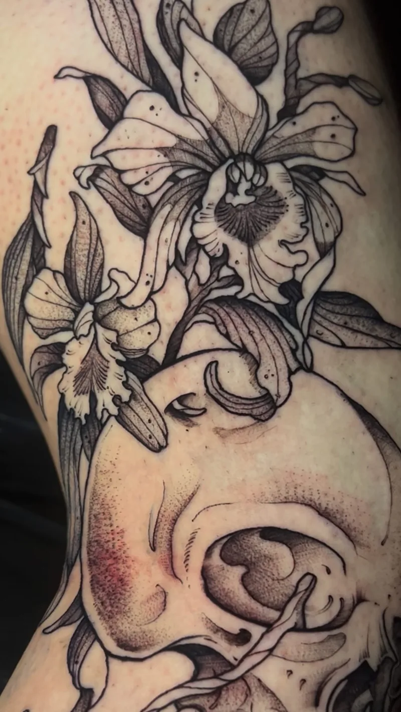 Detalhe de tatuagem floral em tinta preta com lírios, um olho e sombreamento em pontilhismo