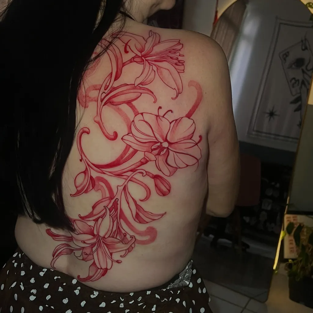 Tatuagem ornamental em tinta vermelha com flores e arabescos cobrindo as costas e o ombro, feita em Campinas
